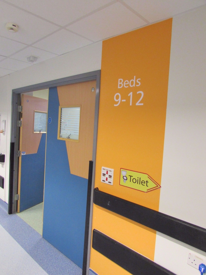 A feature wall stripe and white number stencils help patients to identify their own bed bay