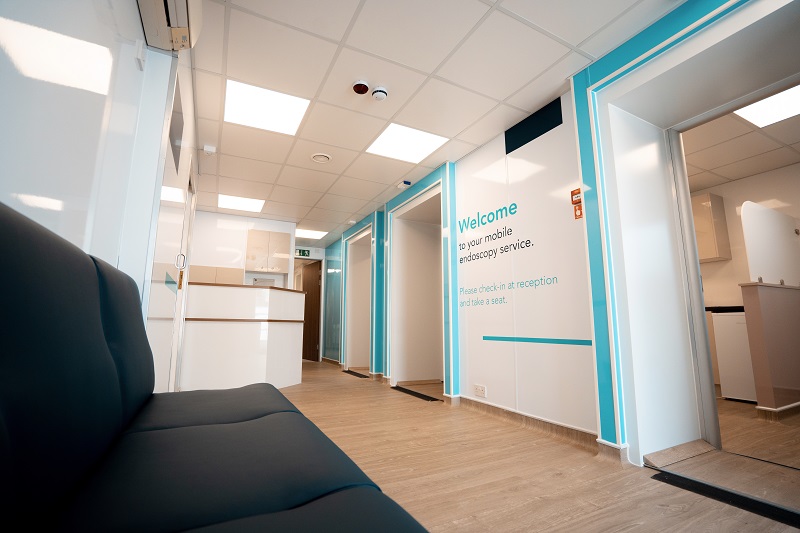 The unit includes consultation rooms, recovery bays, nursing stations, reception areas, bathrooms, and decontamination rooms
